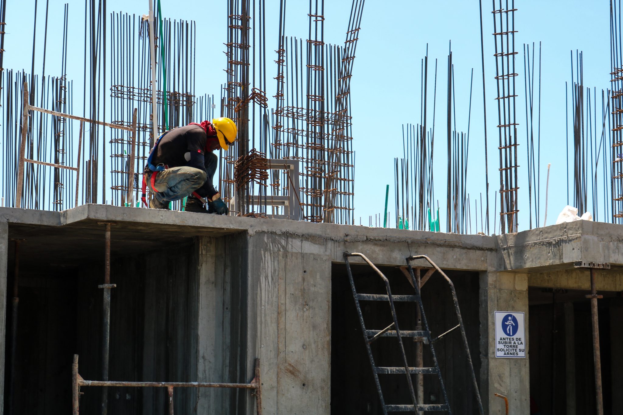 Ein Bauarbeiter mit Helm kniet auf einem unfertigen Bauwerk.